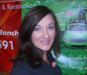 Blue-eyed, brunette lady with a bright smile wearing a collared SERVPRO shirt