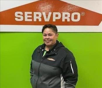Woman standing in front of a green wall with orange SERVPRO logo