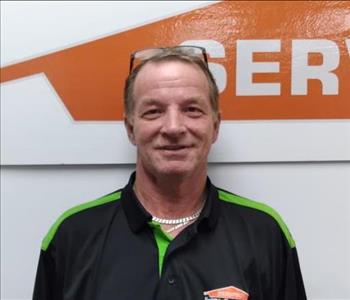 Male crew member standing in front of logo