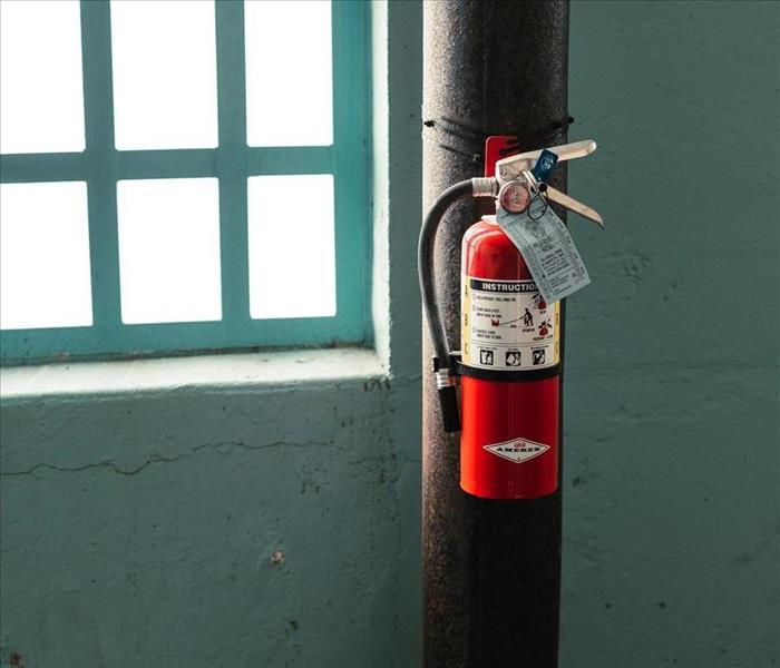 red fire extinguisher on brown pipe near window
