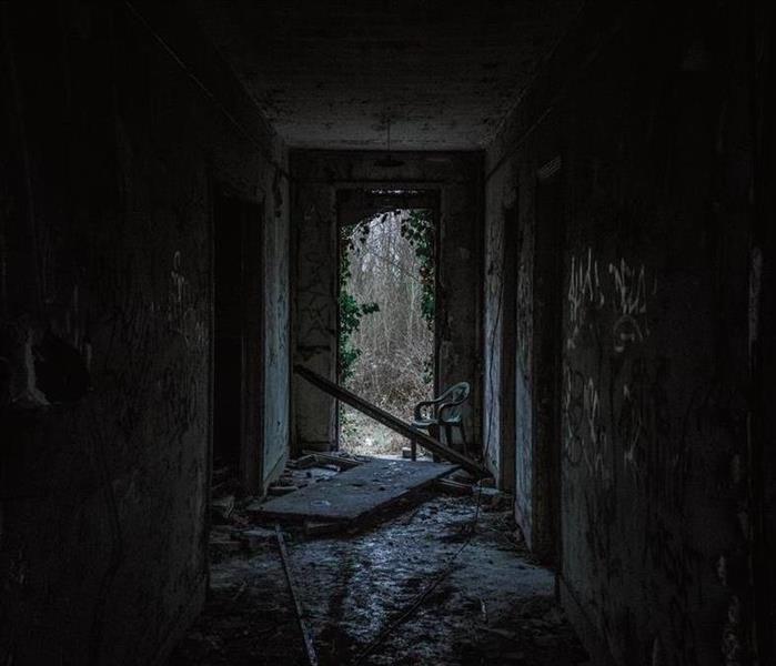 dark hallway with broken door and chair at end