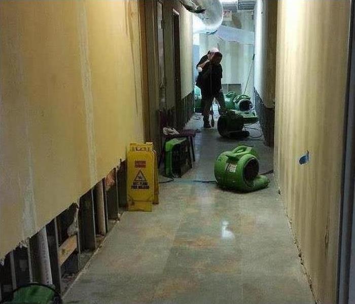Drying equipment in a hallway, left drywall with flood cuts 